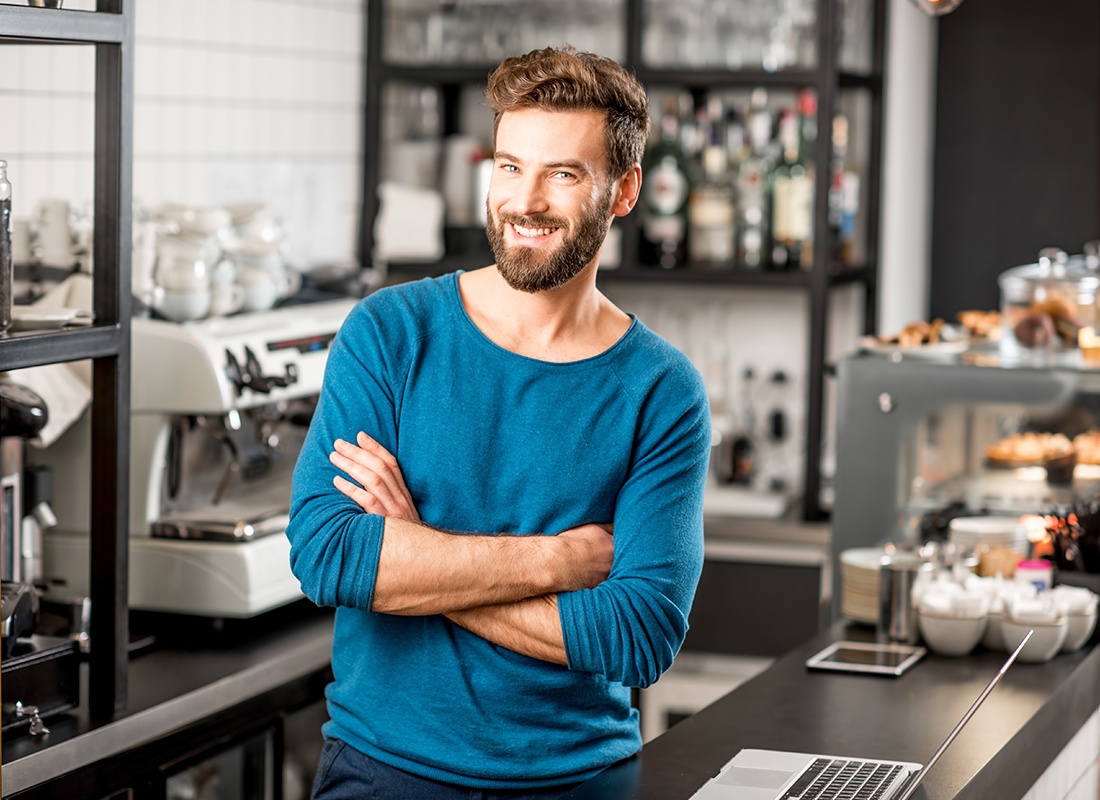 Business Insurance - Cheerful Coffee Shop Owner Leans on a Counter